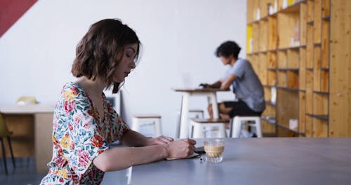 A Woman Writing Notes While Having A Coffee