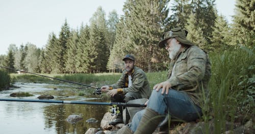 Two Persons Fishing in the River While Talking to Each Other