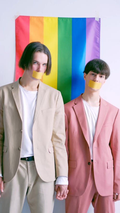 Two Men Standing in Front of a Gay Pride Flag