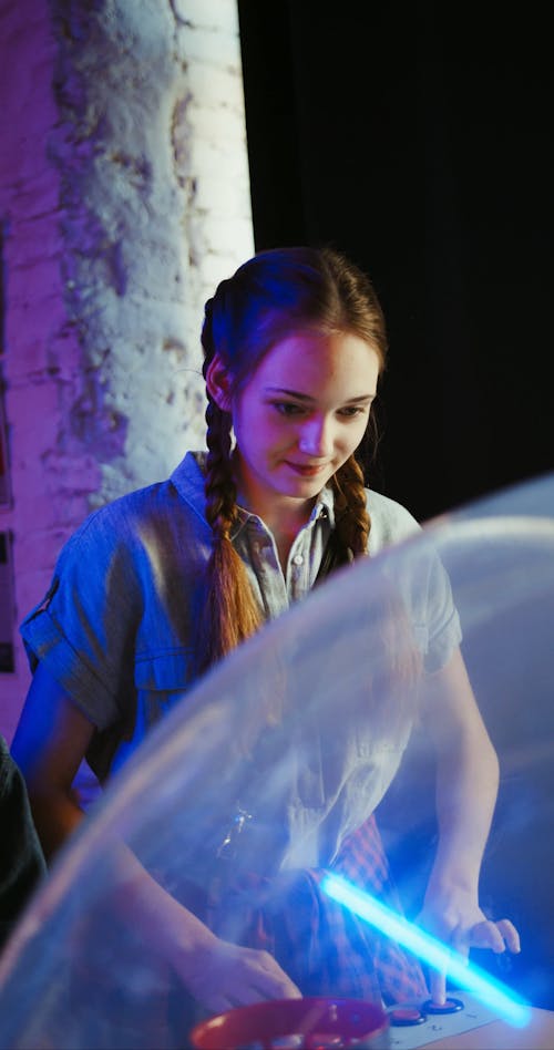 A Young Lady Playing An Arcade Machine