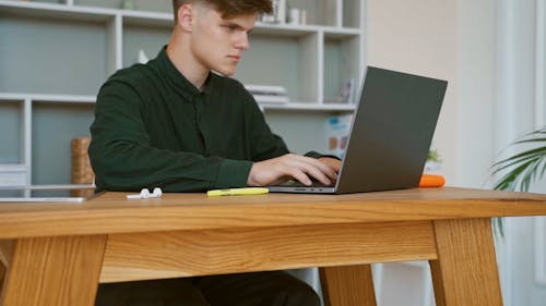 A Young Man Typing on a Laptop