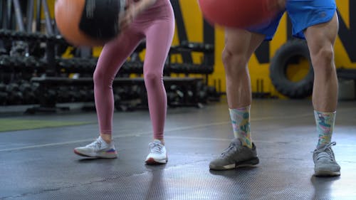 A Man and Woman Doing Squat Exercise With a Medicine Ball