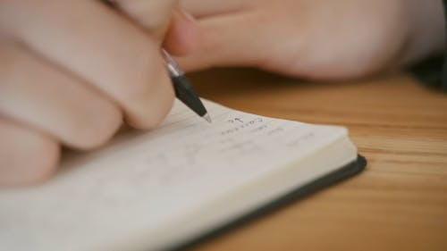 A Person Writing on a Notebook