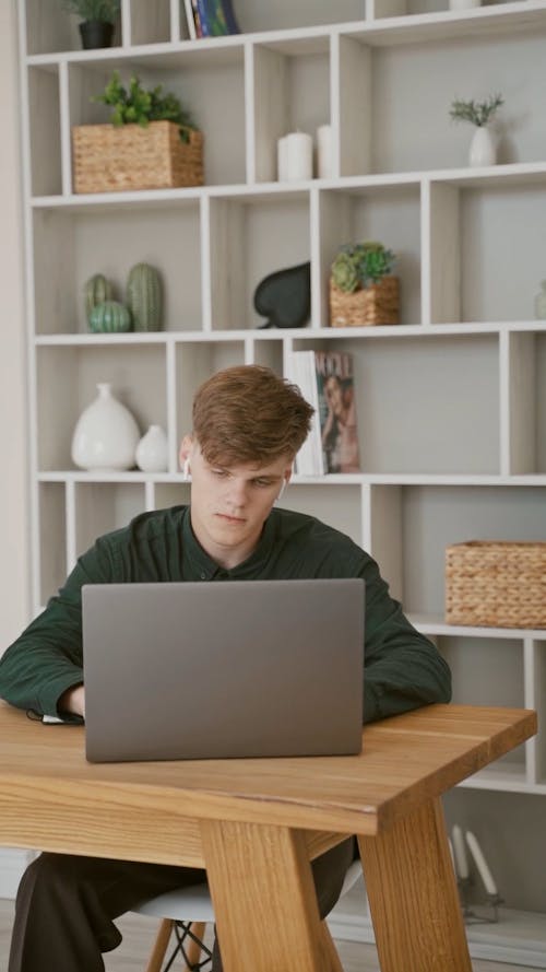 Man in Dark Green Long Sleeves Closing His Laptop and Looking Tired