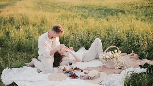 A Couple Having a Picnic In A Grass Field