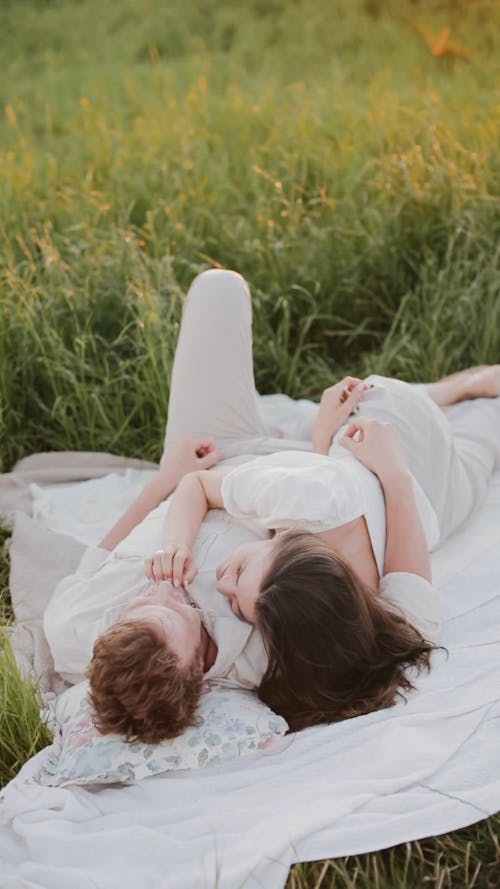 Couple Lying Down on White Picnic Blanket