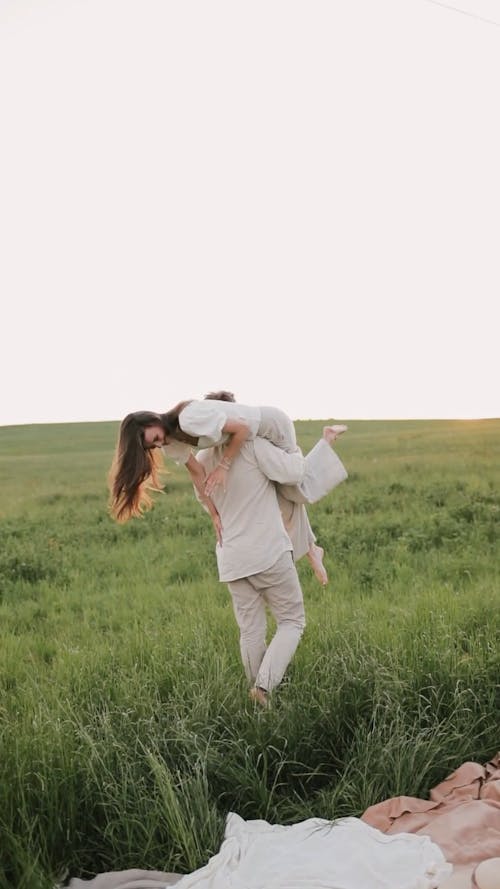Man Carrying His Woman While Walking on Grass Field