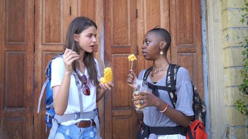 Two Women Eating Pineapple Fruit Wrapped In Plastic