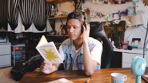 Person Listening to a Music While reading a Book