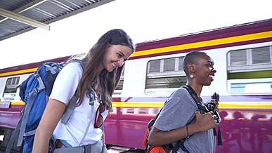 two women walking on railway platform while smiling