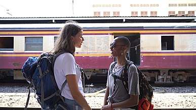 two women talking to each other while standing on railway platform