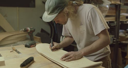 A Man Marking An Unfinished Skateboard