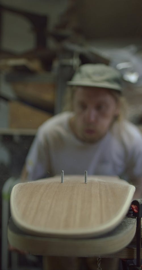 Man Blowing Off the Dust from a Skateboard in Progress