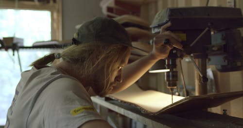 A Craftsman Using a Drilling Machine in Making a Skateboard