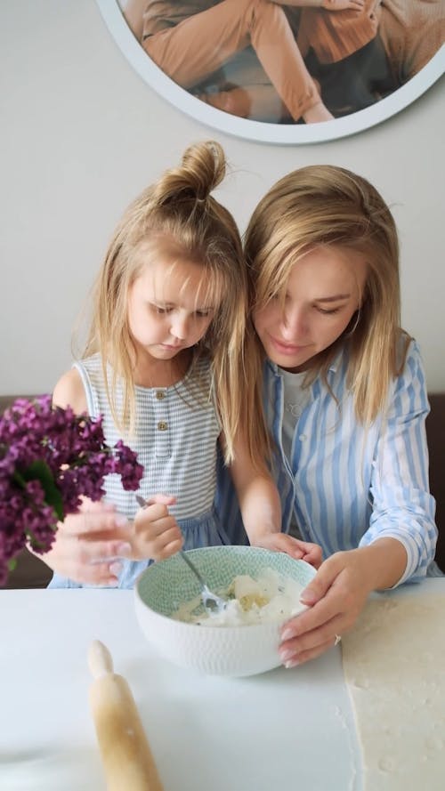 A Mother And Daughter Mixing A Dough In a Bowl