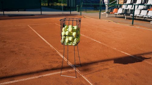 A Tennis Players Picking Balls From a Basket