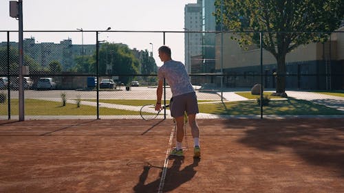 A Tennis Player Practicing His Serving Game