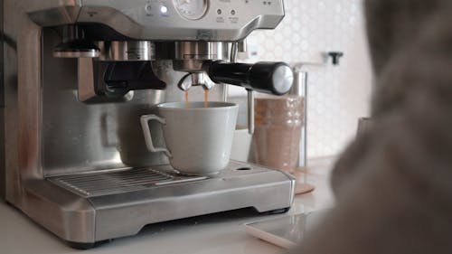 A Person Making a Cup of Coffee Using a Coffee Machine