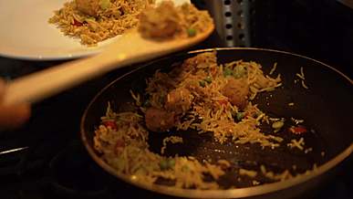 person getting yellow cooked rice from frying pan