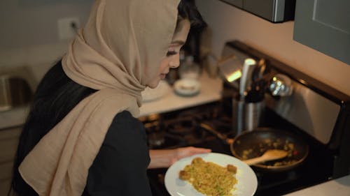 Woman in Hijab Holding a Plate With Yellow Cooked Rice