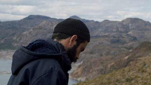 Man in Black Beanie Taking Photos Using a Black Camera