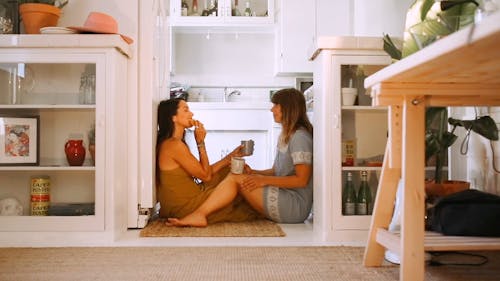 Women Having Snacks While Sitting On The Kitchen Floor