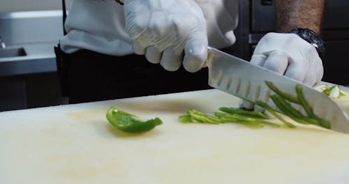 Person Slicing a Green Bell Pepper