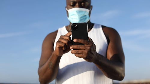 Person Wearing a Facemask Checking His Phone