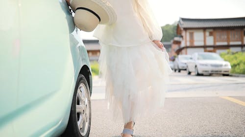 Woman in White Dress Showing a Traditional House