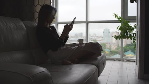 Woman Sitting on Sofa Using Cellphone