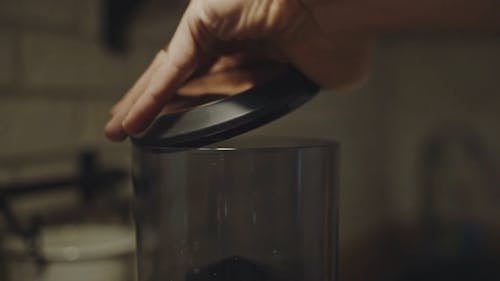 Close-Up View of Person Pouring Roasted Coffee Beans in a Coffee Machine