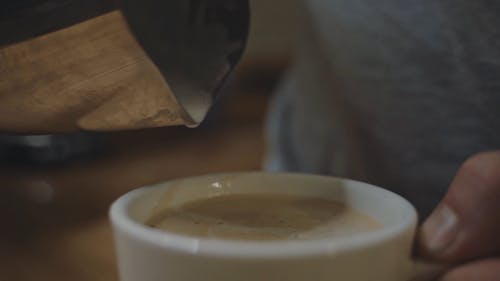 Close-Up View of a Person Pouring the Milk on His Coffee Drink