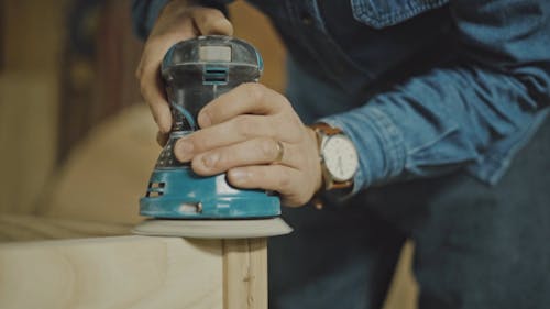 A Person Using a Grinding Machine to Smoothen the Wooden Surface