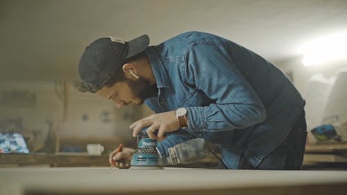 A Joiner Using a Grinding Machine to Smoothen the Wooden Tabletop