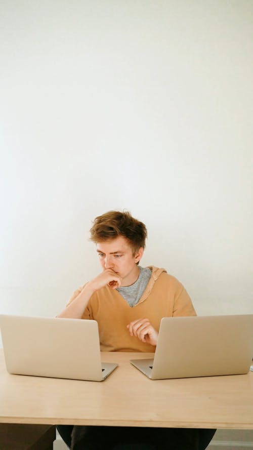 Man Sitting while Using Two Laptops