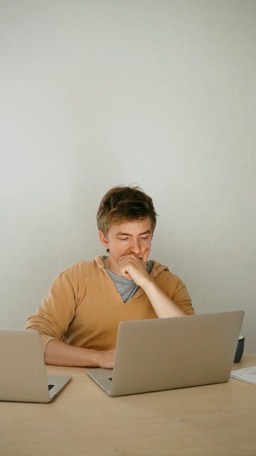 Man Drinking a Beverage while Looking at Laptop