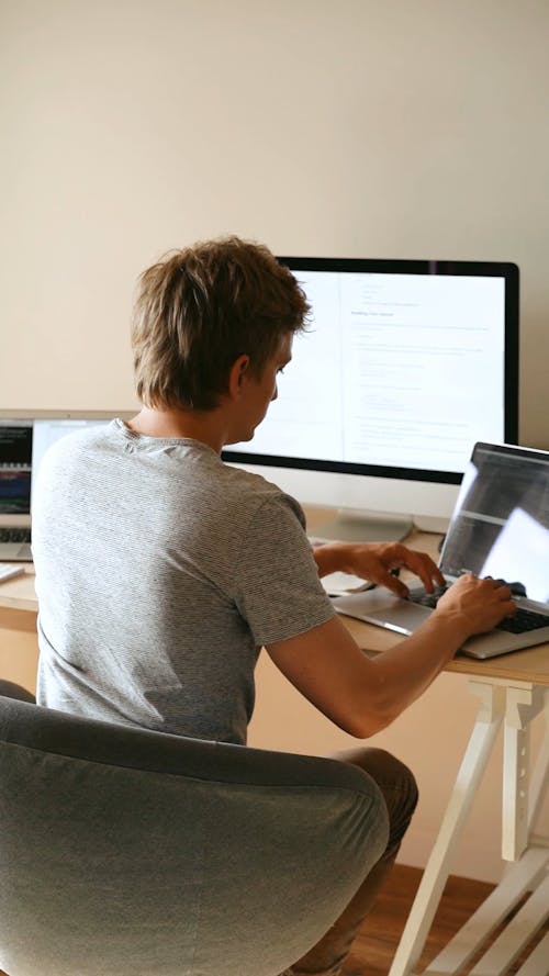 Back View of a Man Typing on Laptop