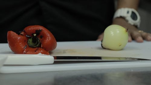 Person Slicing a Onion and Bell Pepper