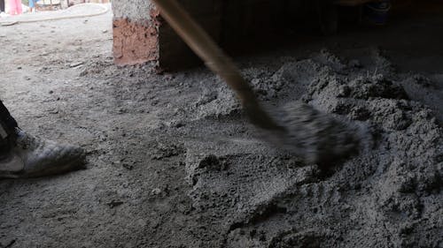 Person Mixing a Cement with a Shovel