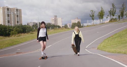 Young Girls Riding a Longboard on the Road
