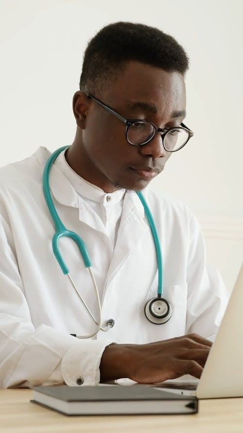 Man in White Lab Coat Using a Laptop