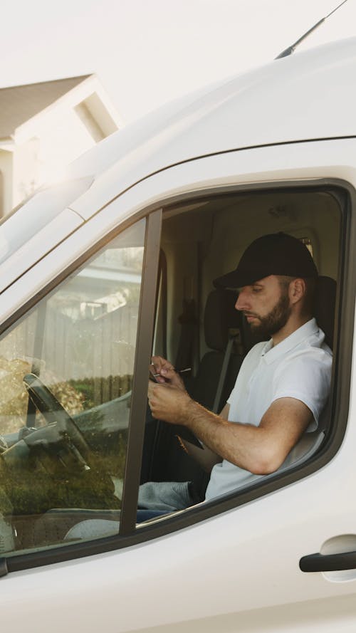 Delivery Man Writing on a Notepad inside a Van