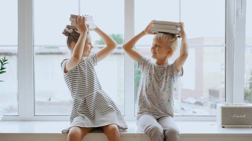 Brother and Sister With Books on Their Heads