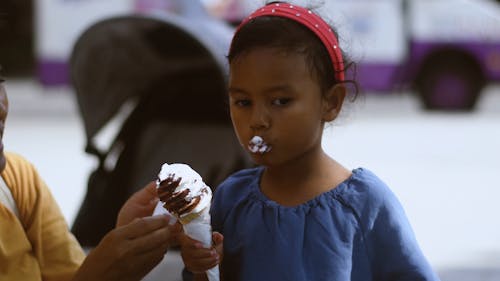 Woman Cleaning Daughter's Face while she Enjoys Ice Cream