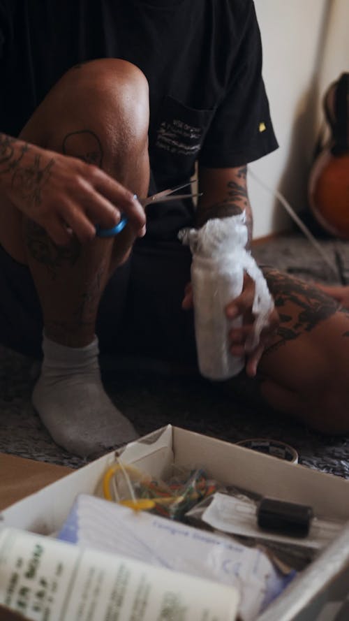 Tattooist opening Ink Bottle with scissors 