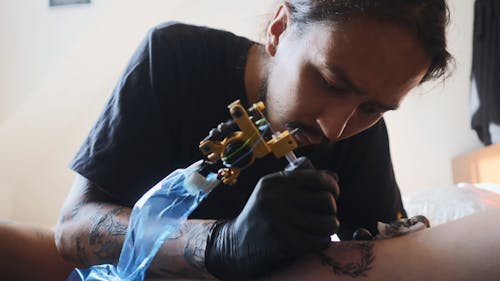 Close-Up View of a Man Tattooing Arm of a Person