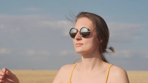 Woman Removing Sunglasses and Looking at Sun