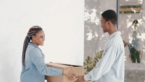 Woman Giving Cardboard Boxes to a Guy