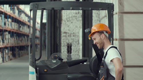 Man with Orange Helmet Getting into Forklift