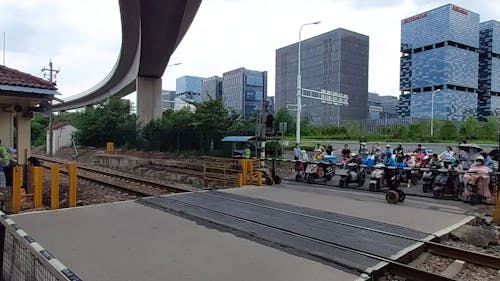 People Waiting at Railway Crossing for Freight Train to Pass